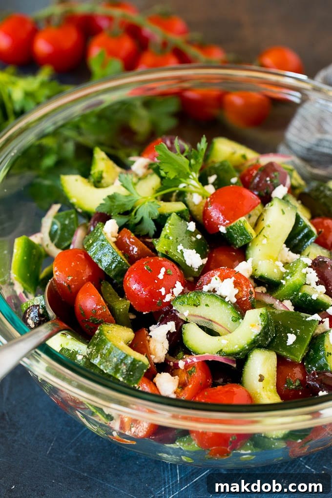 Fresh Mediterranean Salad 6 A spoon in a bowl of Mediterranean salad that is garnished with feta cheese and fresh herbs.