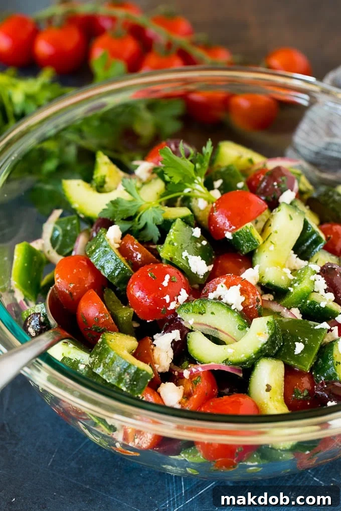 Mediterranean Sunshine Salad 6 A spoon in a bowl of Mediterranean salad, garnished with crumbled feta cheese and fresh parsley.
