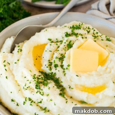 Cook-Ahead Creamy Mash 3 A bowl of make ahead mashed potatoes topped with butter and herbs.