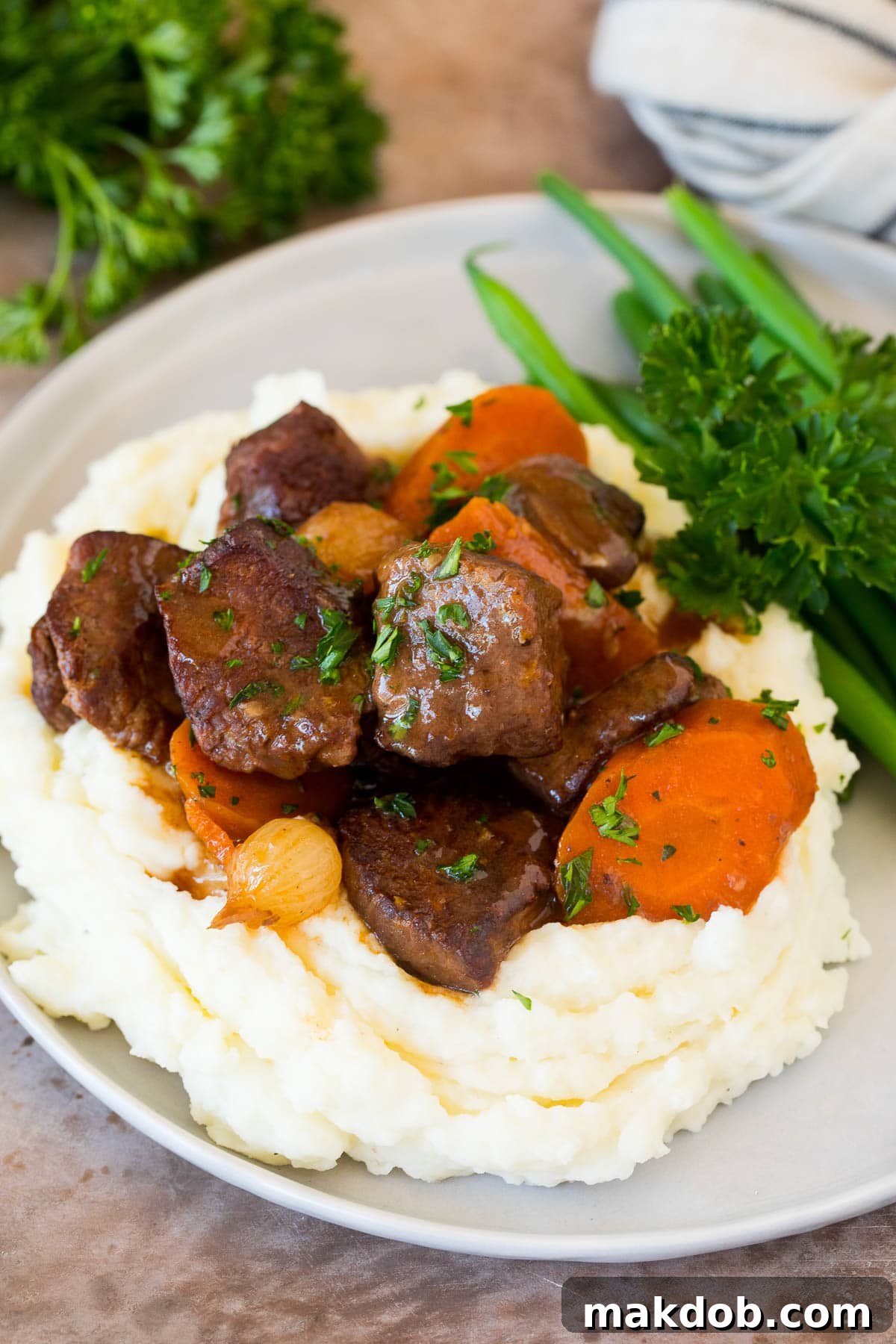 These make ahead mashed potatoes are Russet potatoes that are boiled until tender, then combined with butter, garlic, cream cheese and seasonings to make the ultimate side dish. Tender beef served over a generous pile of make ahead mashed potatoes, garnished with herbs.