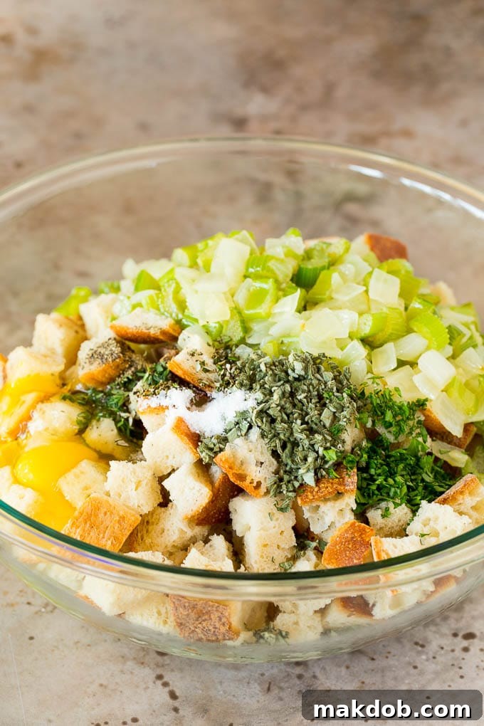A large mixing bowl filled with dried bread cubes, sautéed onions and celery, and fresh eggs, ready to be combined into a delectable stuffing.
