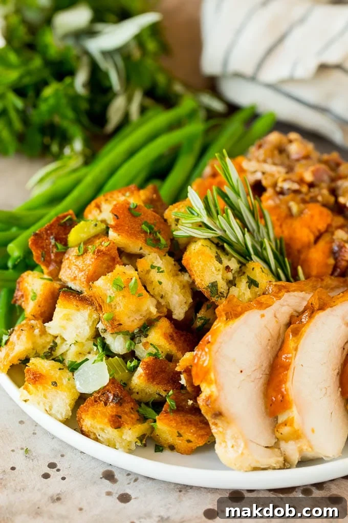 A festive Thanksgiving plate featuring a generous serving of golden-brown stuffing, accompanied by sliced turkey, sweet potatoes, and fresh green beans.