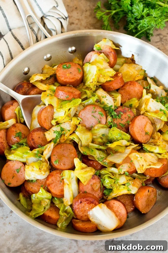 This cabbage and sausage skillet is a combination of smoked sausage, vegetables and savory seasonings, all cooked together to make a quick and easy dinner. A pan of cabbage and sausage with parsley and a serving spoon.