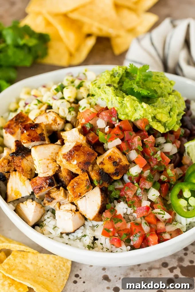 Chipotle chicken in a bowl with rice, salsa, beans and guacamole.