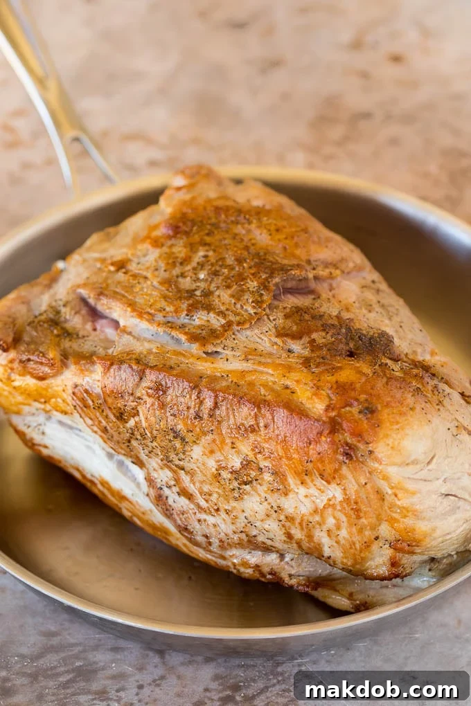 A browned pork shoulder in a pan.