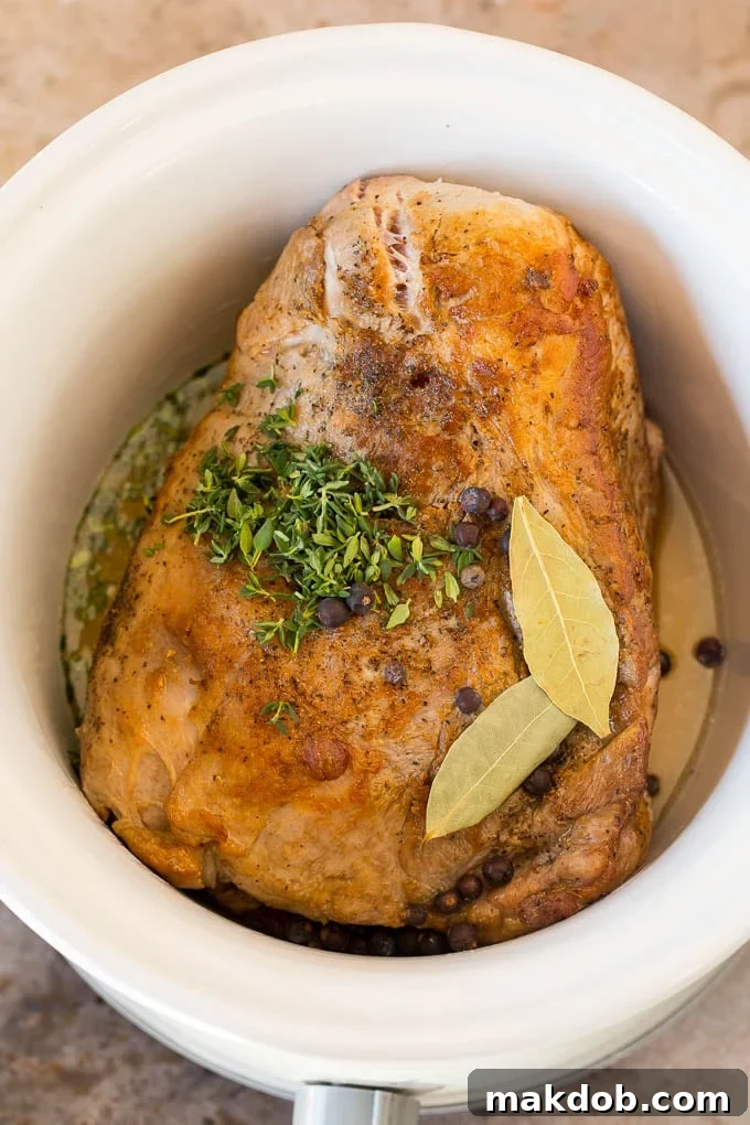 Pork in a slow cooker with chicken broth, bay leaves, thyme and juniper.