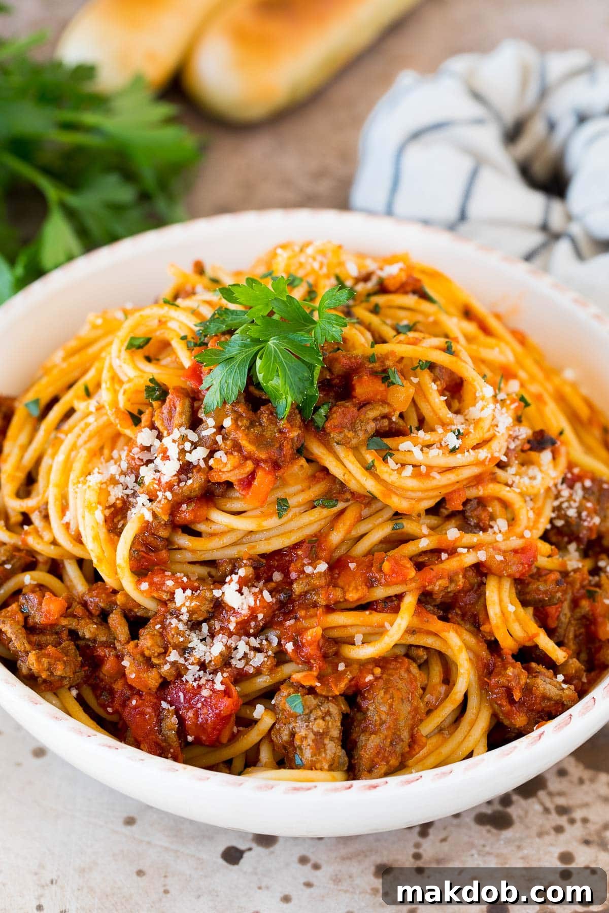 Hearty slow cooker bolognese sauce served generously over a bed of spaghetti, garnished with fresh parsley.