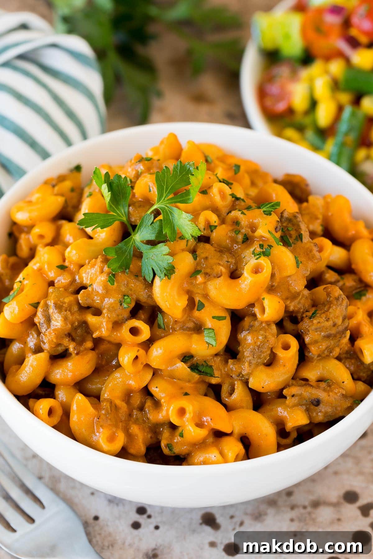 A beautifully presented bowl of homemade hamburger helper, garnished with fresh parsley, ready to be served. The rich red sauce and golden macaroni noodles are clearly visible, promising a comforting meal.