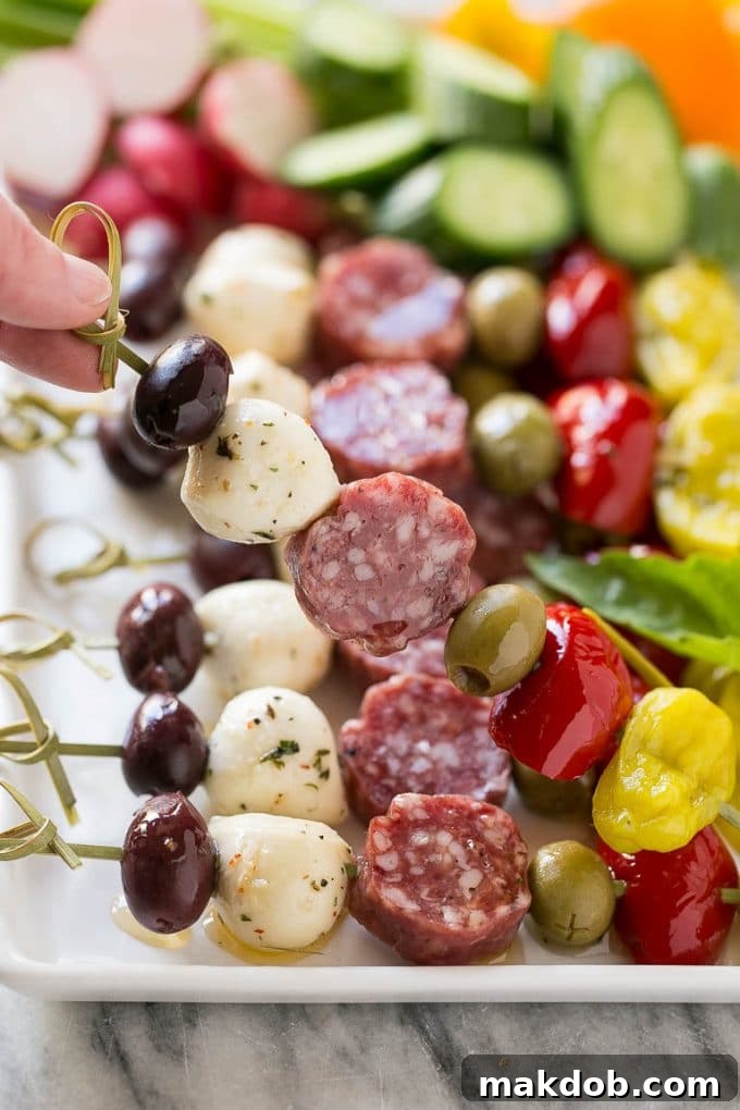 Antipasto Skewers Recipe | Easy Antipasto | Best Antipasto | Party Food #antipasto #skewers #appetizer #dinneratthezoo A hand presenting a single antipasto skewer, showcasing a perfect combination of salami, mozzarella cheese, and vibrant olives.