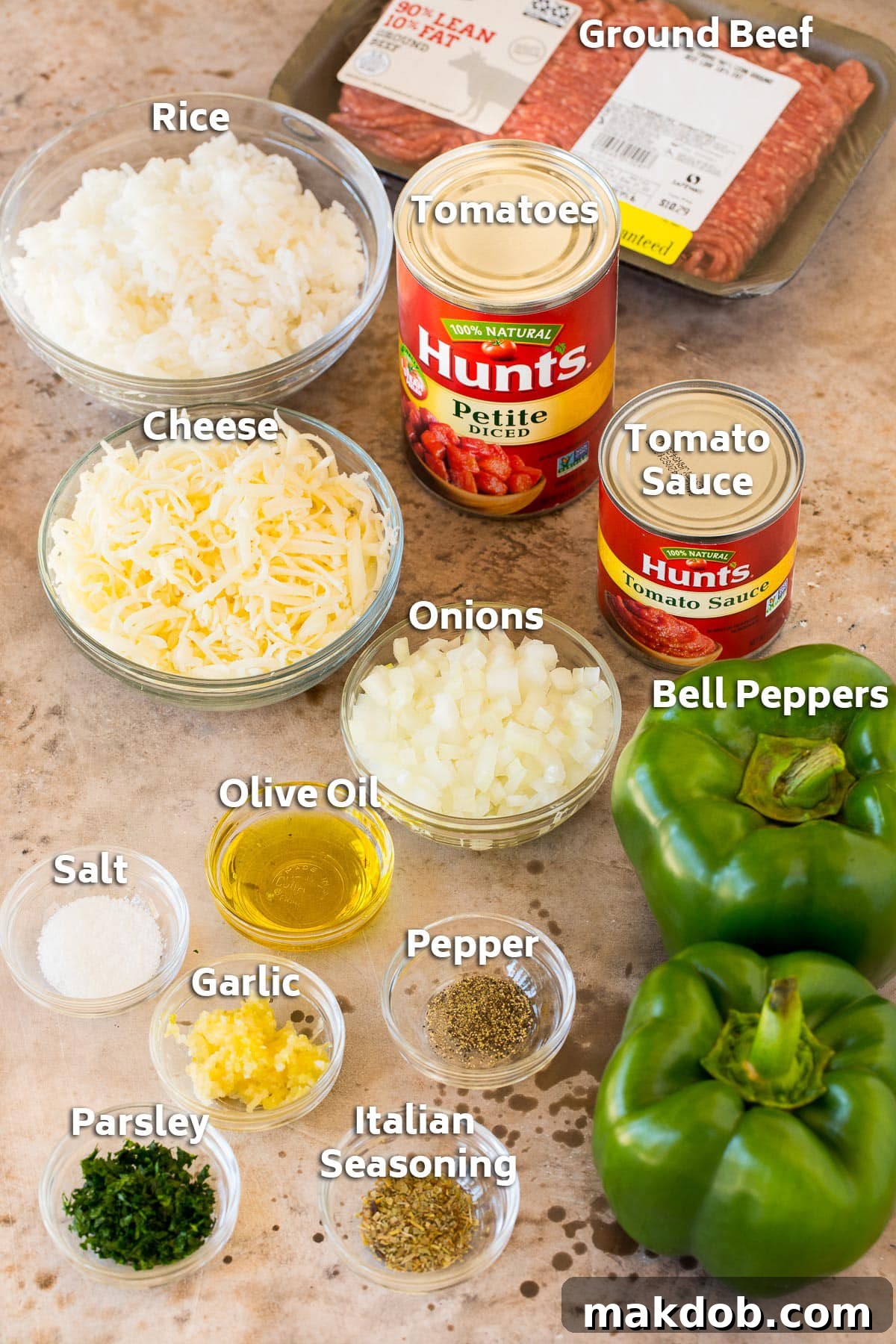 Ingredients for stuffed green peppers laid out on a counter, including bell peppers, rice, ground meat, cheese, and various seasonings.