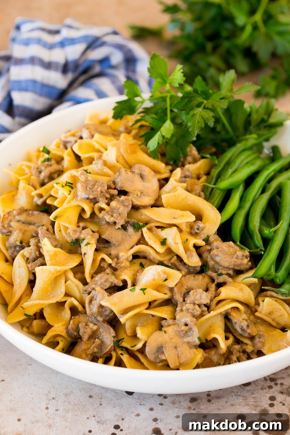 Creamy Ground Beef Stroganoff Comfort 6 A serving bowl filled with ground beef stroganoff and a side of green beans.