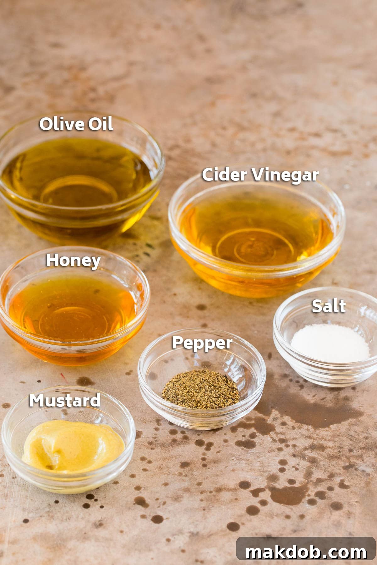Bowls of ingredients for the homemade salad dressing: olive oil, apple cider vinegar, honey, Dijon mustard, salt, and pepper.