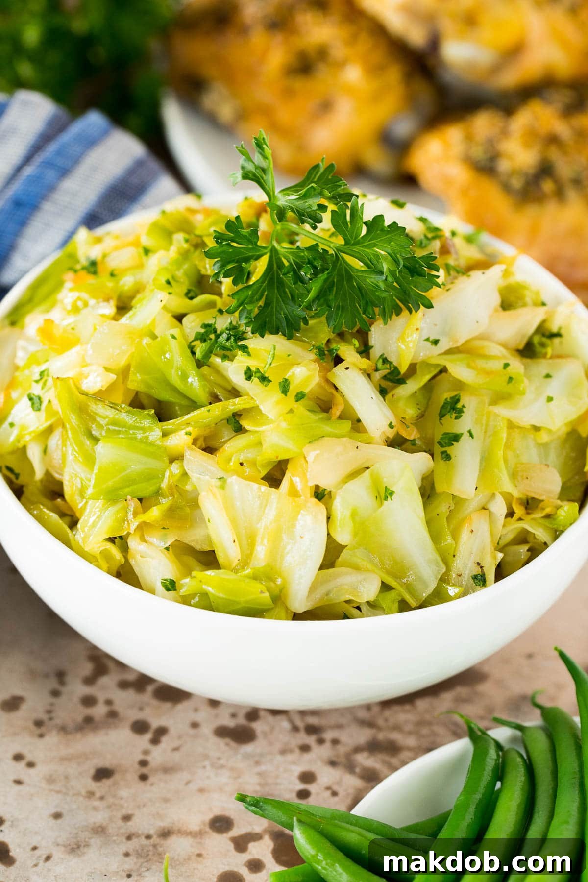 A bowl of sauteed cabbage served alongside perfectly cooked chicken and crisp green beans.