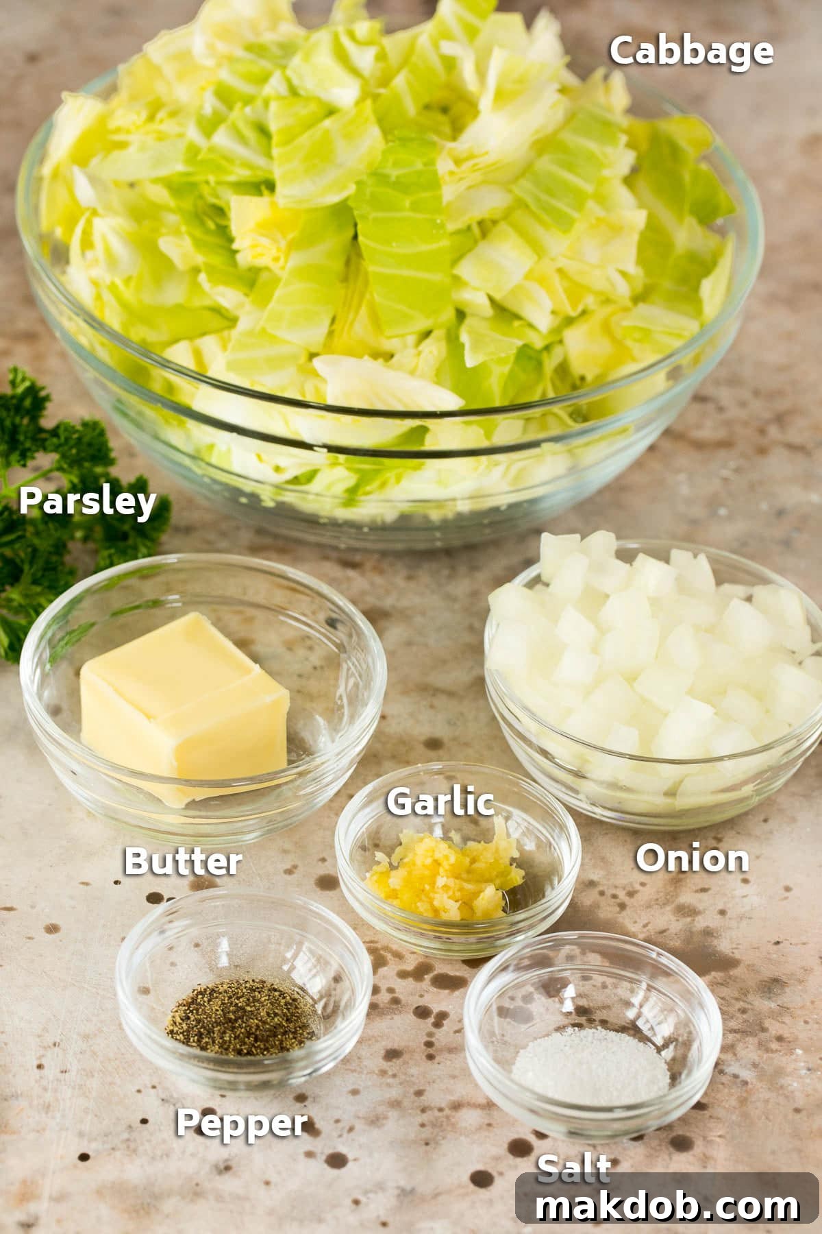 Bowls containing fresh cabbage, chopped onion, butter, and various seasonings, ready for cooking.