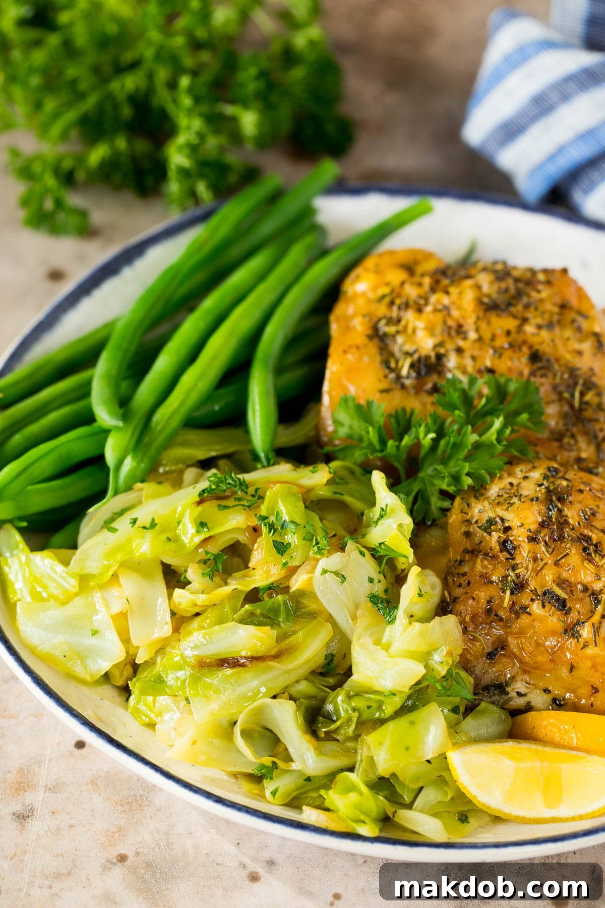 A beautifully arranged plate featuring steamed green beans, perfectly cooked chicken thighs, and a generous portion of savory sauteed cabbage.