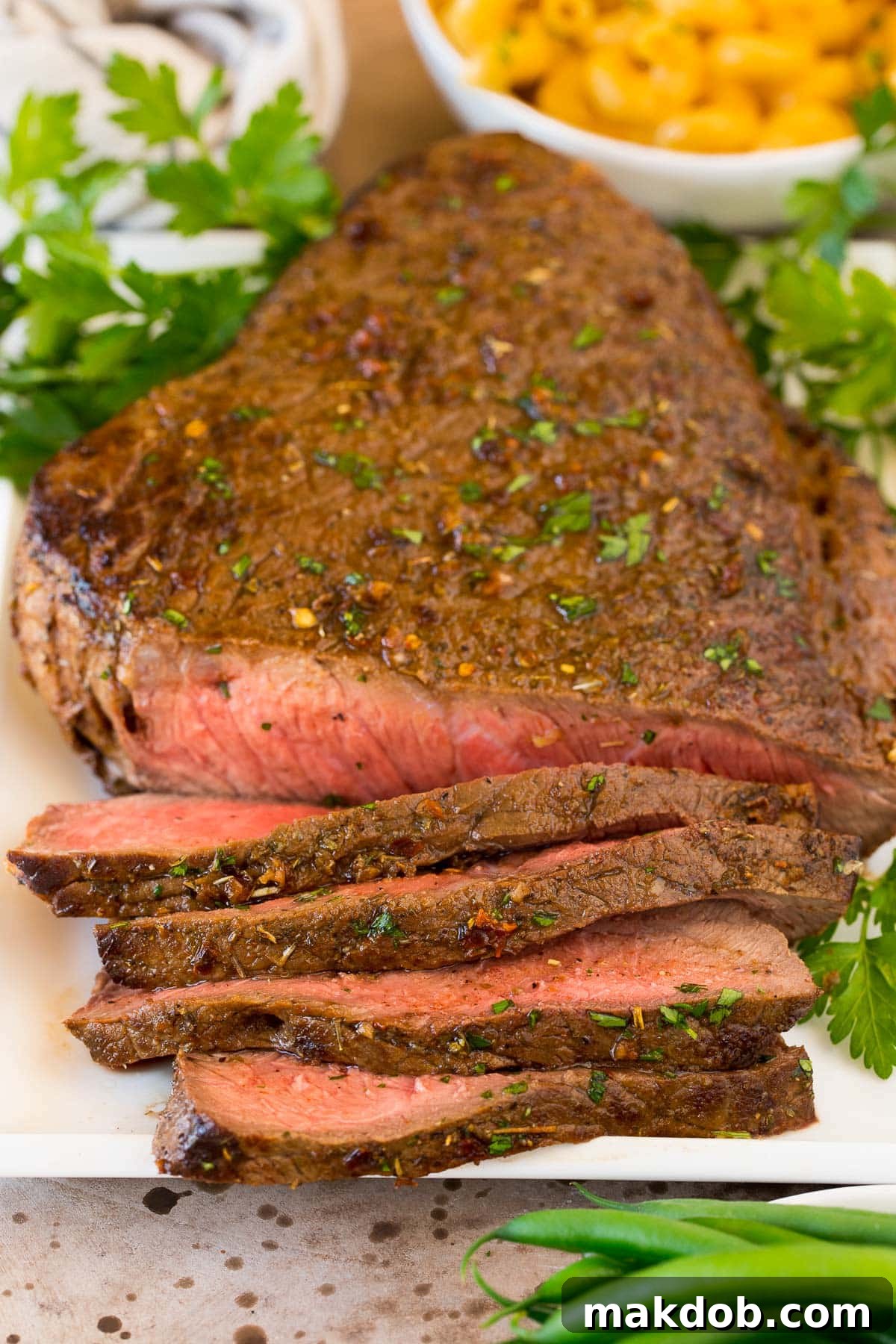 London broil on platter partially sliced, showcasing its tender interior and rich color.