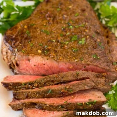 London broil on platter partially sliced, showcasing its tender interior and rich color.
