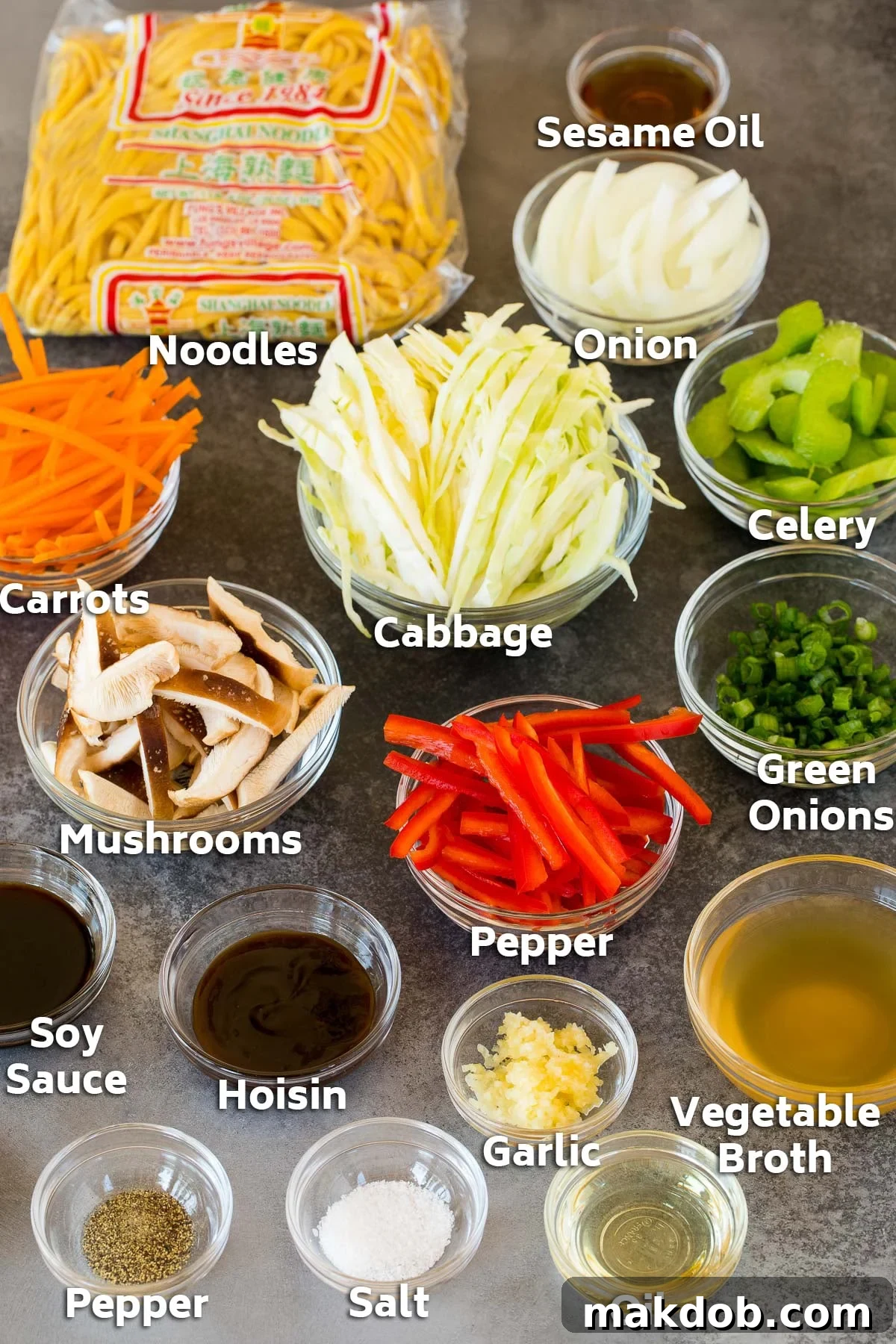 Vibrant Vegetable Lo Mein 3 Bowls filled with prepped ingredients including thinly sliced vegetables, fresh noodles, and a mixed savory sauce, ready for cooking.