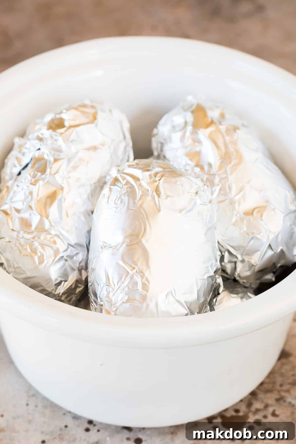 Potatoes wrapped in foil in a slow cooker.