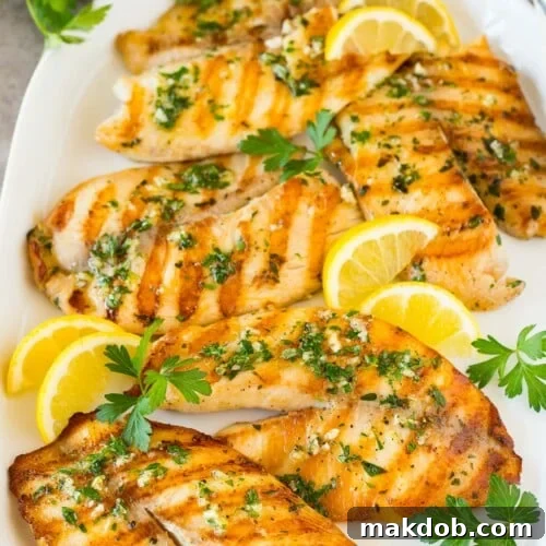 A platter of grilled tilapia fillets garnished with lemon and parsley.