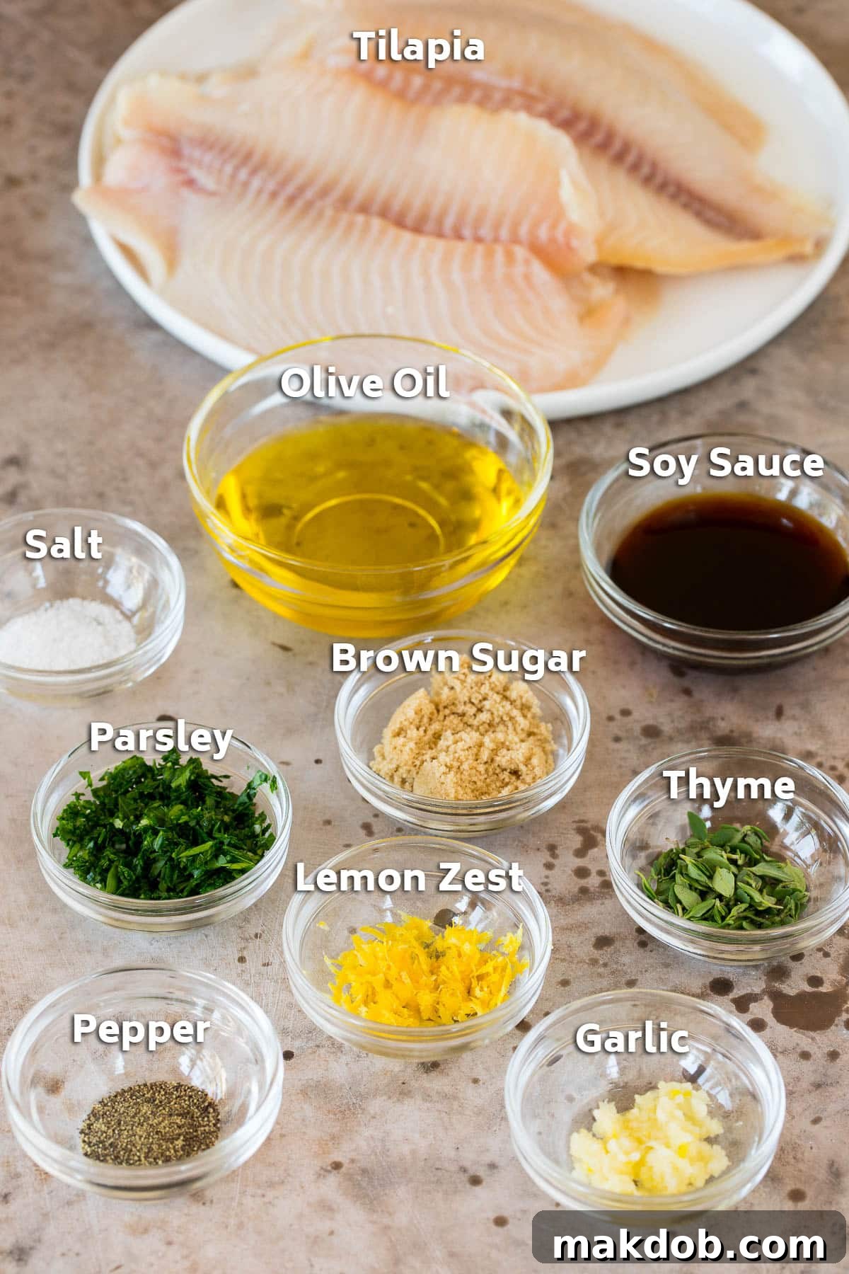 A curated display of fresh ingredients for grilled tilapia: fish fillets, olive oil, soy sauce, aromatic herbs, and essential seasonings.