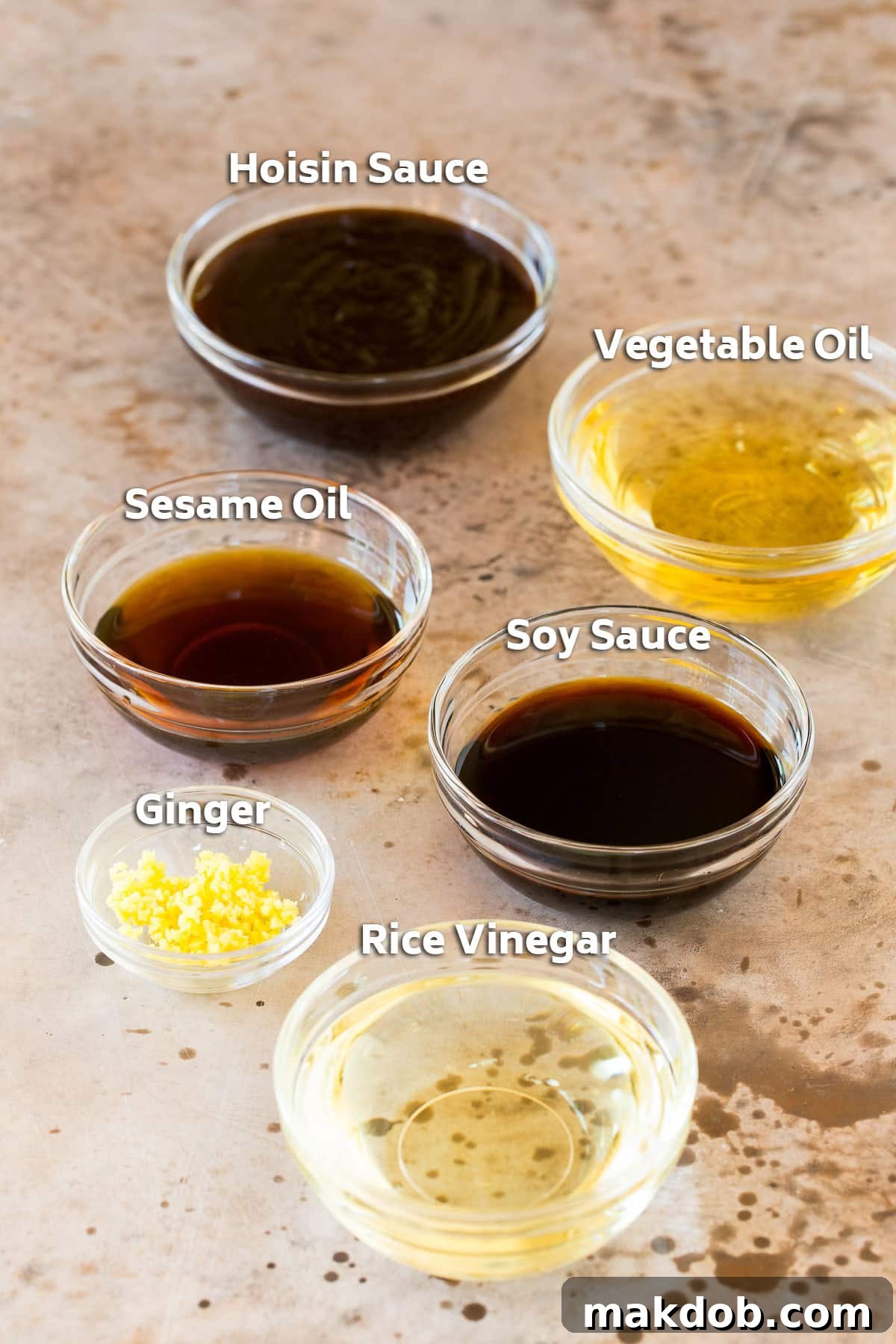 Bowls of essential ingredients, including vegetable oil, soy sauce, hoisin sauce, and grated ginger, ready for mixing.