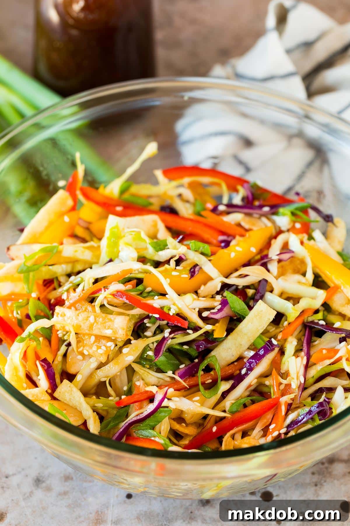 A vibrant salad featuring cabbage, bell peppers, and crispy wontons, generously coated with the Asian salad dressing.