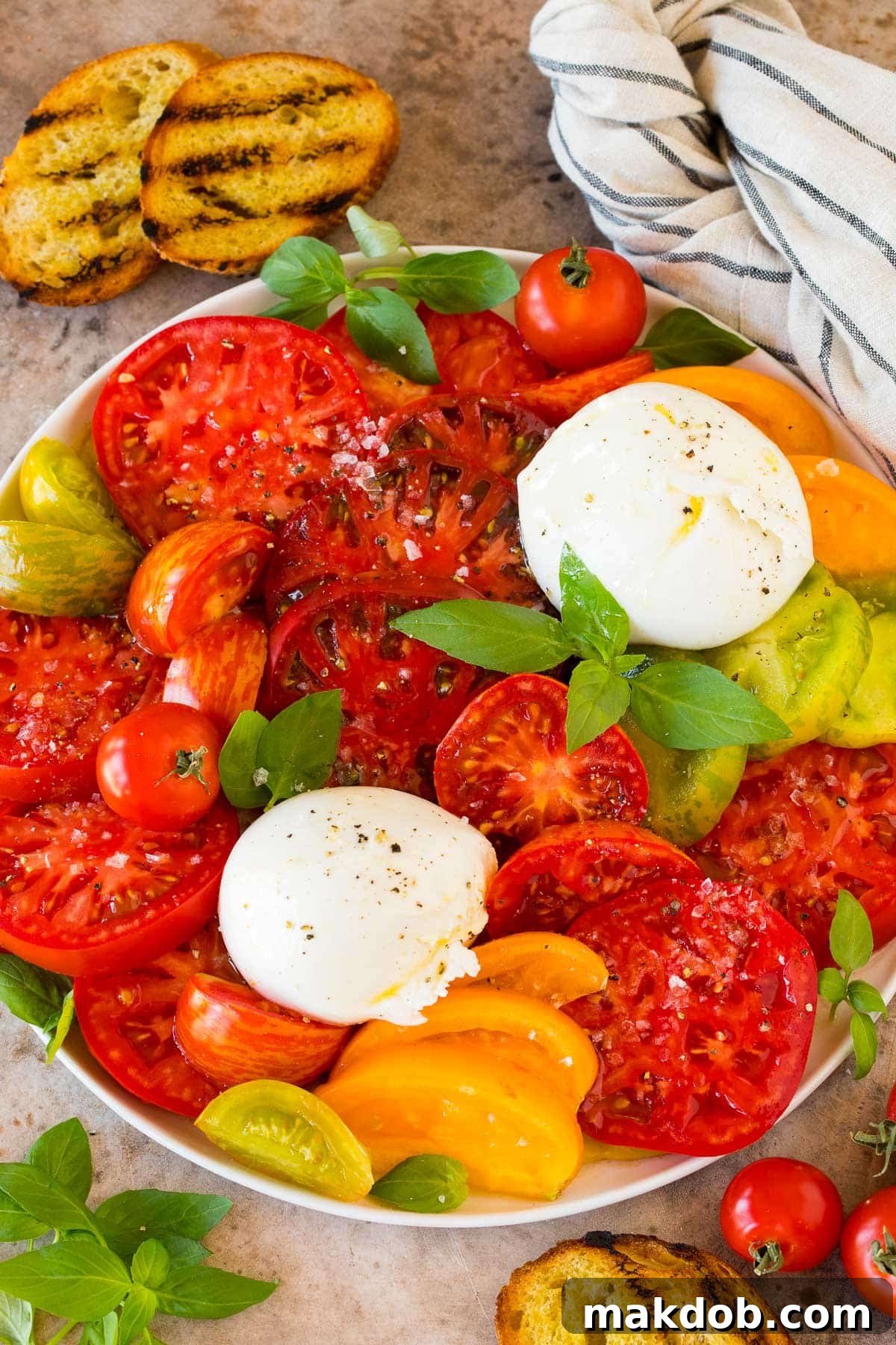 A beautifully arranged platter of burrata salad, showcasing fresh tomatoes, creamy burrata cheese, vibrant basil leaves, and a glistening dressing, ready to be served.