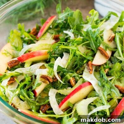 A bowl of fennel salad made with arugula, apples and pecans.