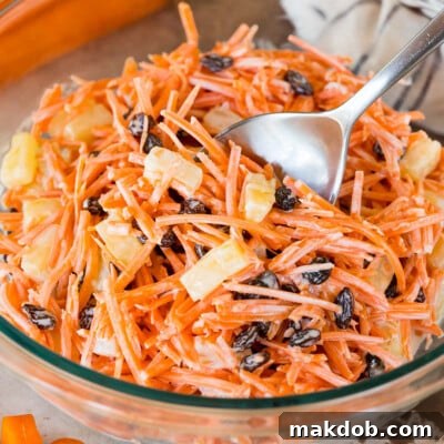 A bowl of creamy carrot salad with a large spoon in it.