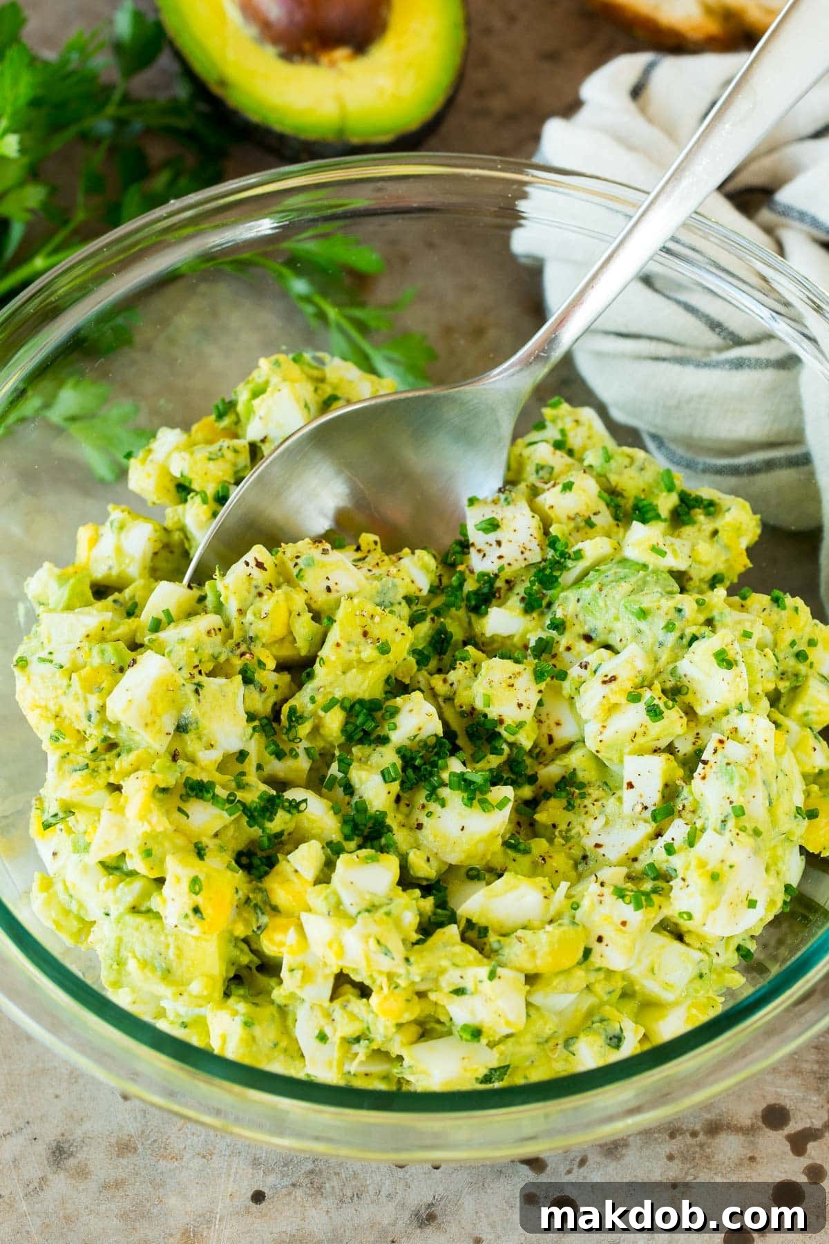 A serving spoon in a bowl of avocado egg salad.