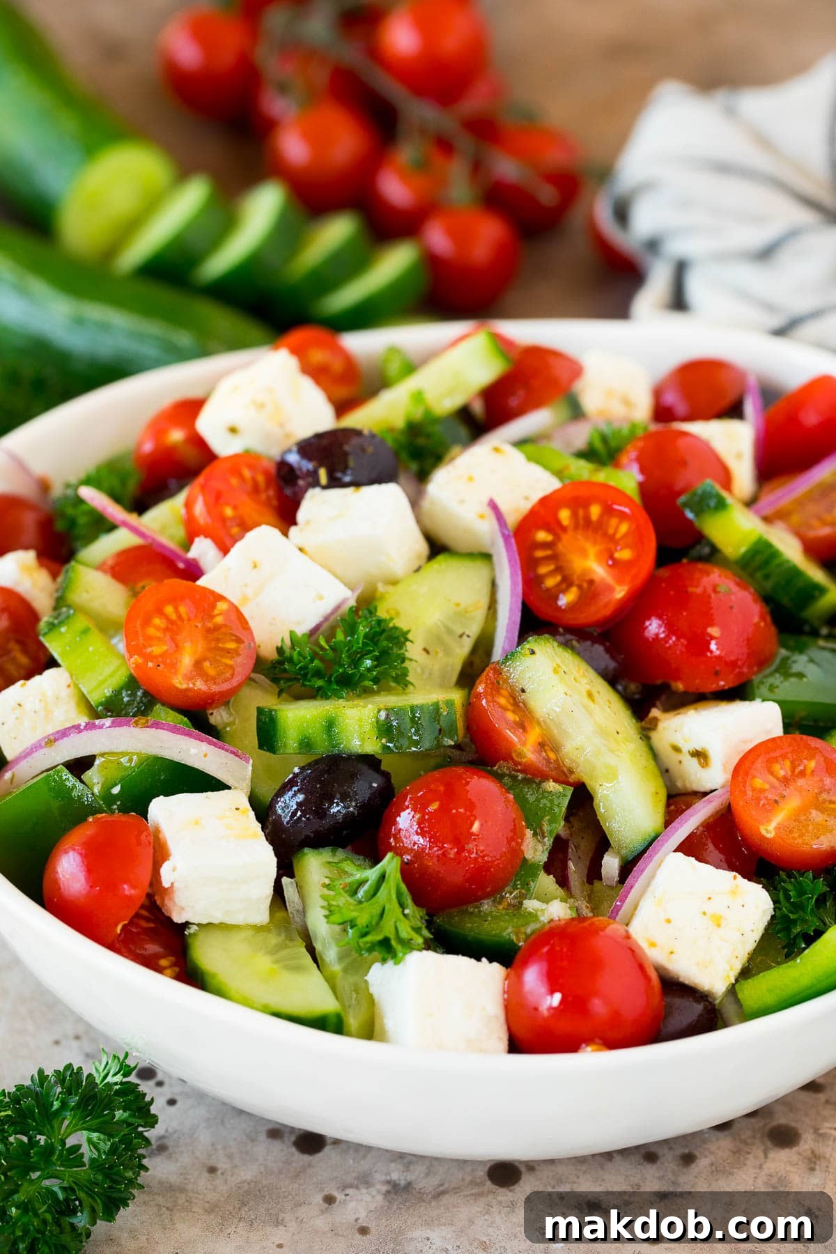 A vibrant chopped Greek salad, brimming with fresh cucumbers, juicy tomatoes, briny Kalamata olives, thinly sliced red onions, and crumbled feta cheese.