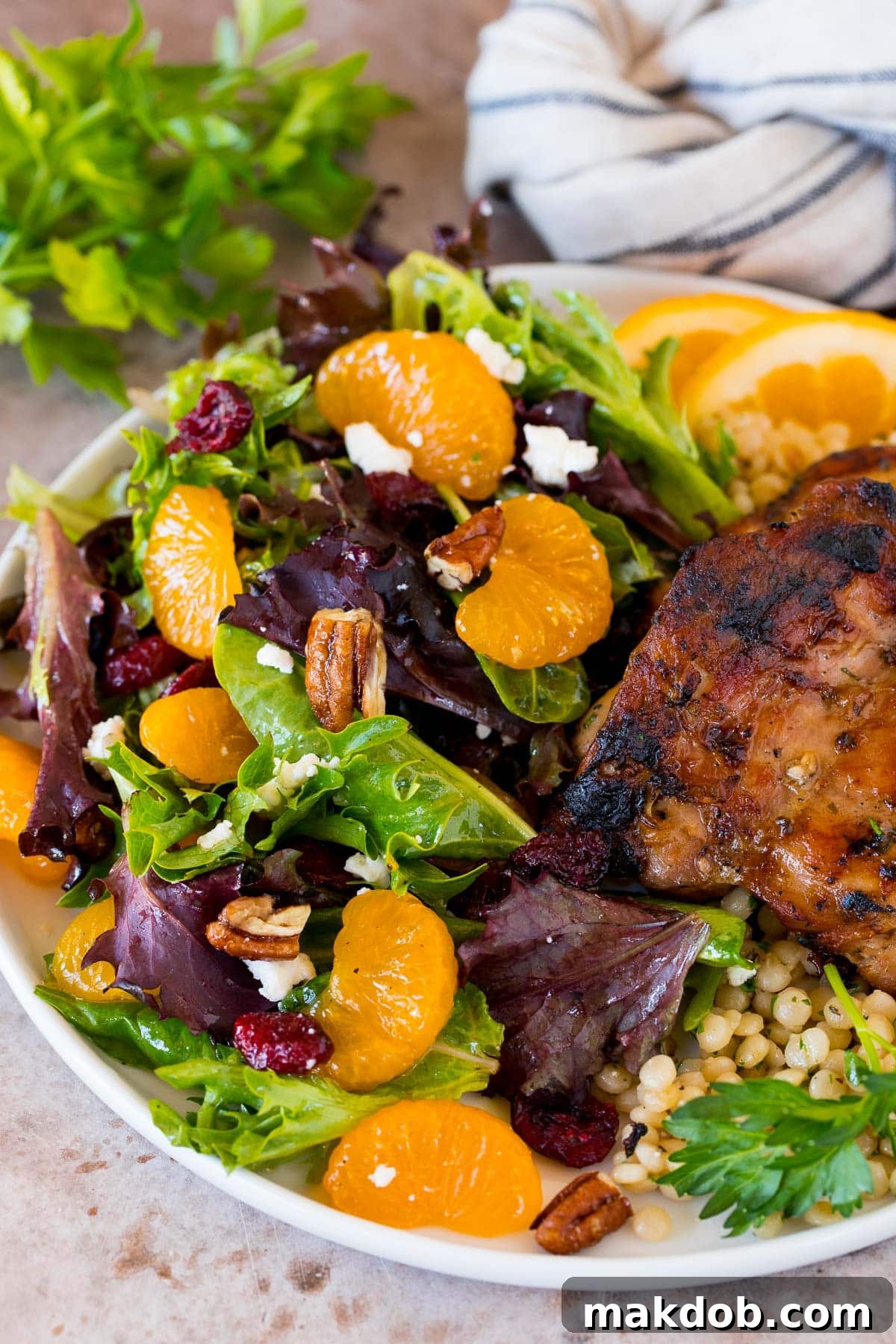 A vibrant plate of Mandarin Orange Salad served as a side dish alongside perfectly cooked chicken, showcasing a complete meal idea.