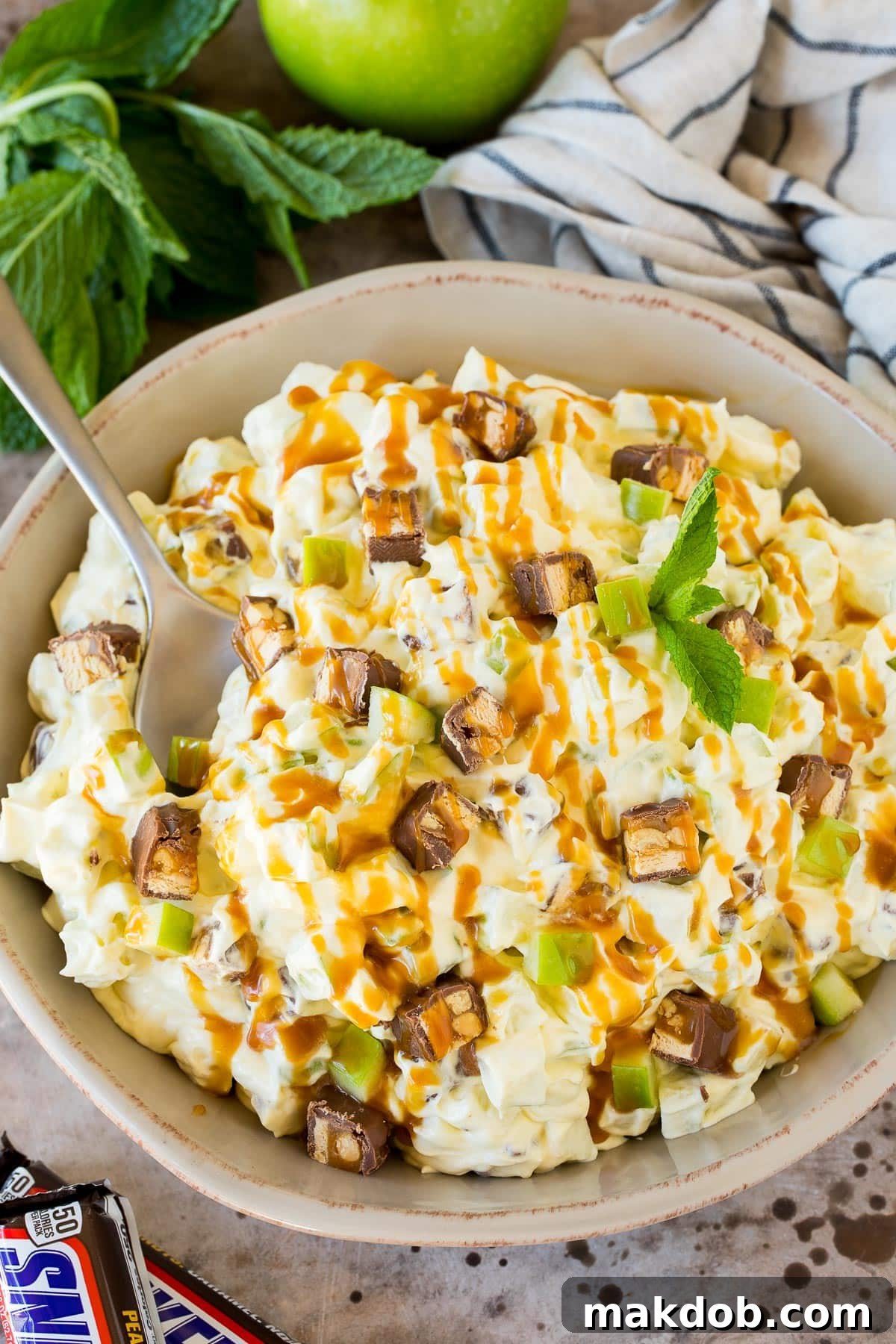 Snickers Apple Delight 6 A bowl of snicker apple salad topped with caramel sauce.