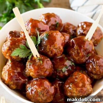 Sticky Grape Glazed Meatballs 7 A bowl of grape jelly meatballs served with cocktail forks.