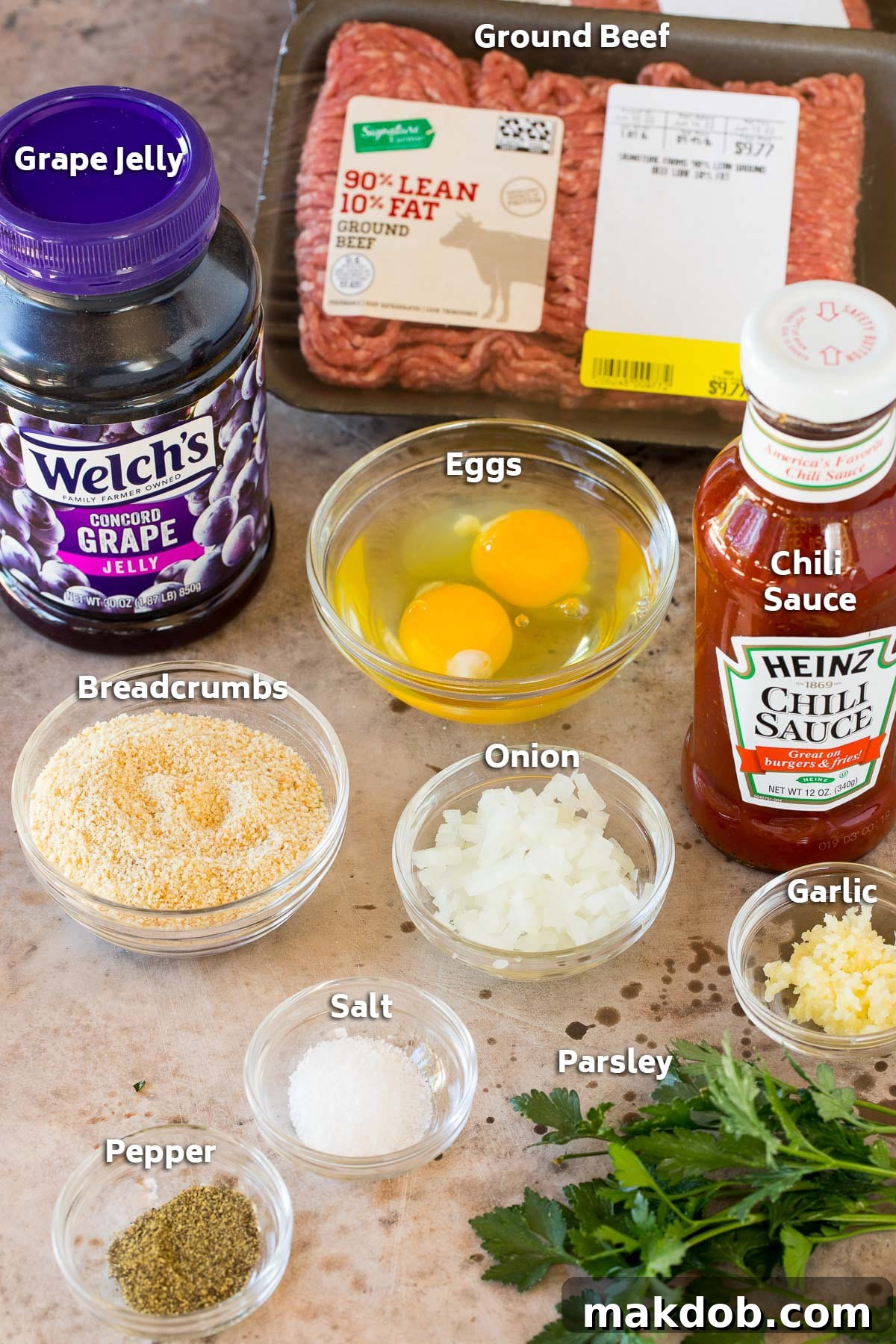 Sticky Grape Glazed Meatballs 3 Ingredients for grape jelly meatballs laid out, including ground beef, eggs, breadcrumbs, seasonings, and a jar of grape jelly.