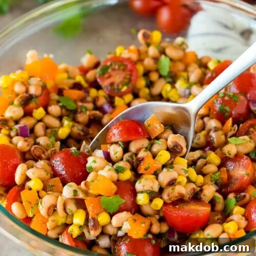 Zesty Black Eyed Pea Salad 7 A spoon in a bowl serving up black eyed pea salad.
