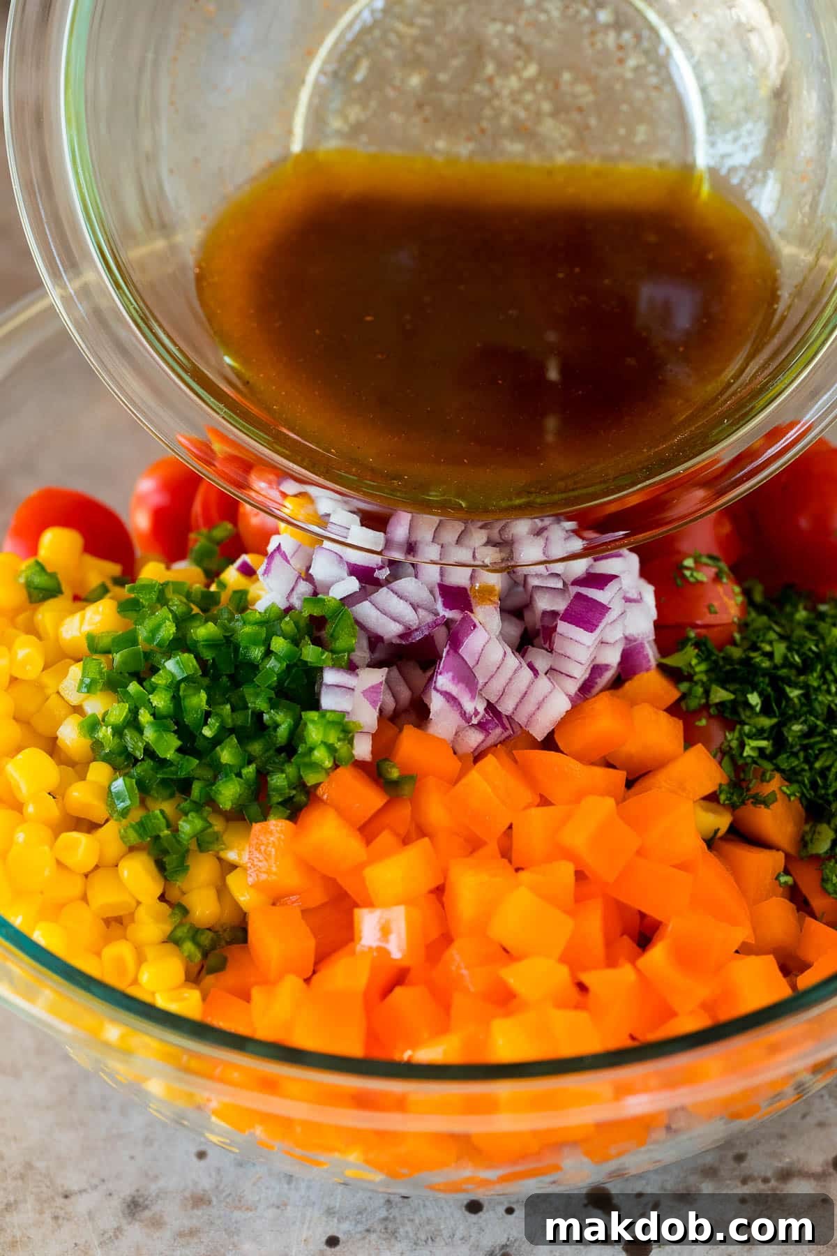 Zesty Black Eyed Pea Salad 5 A stream of zesty dressing being poured over a large bowl of black eyed pea salad, highlighting the vibrant colors of the vegetables and peas.