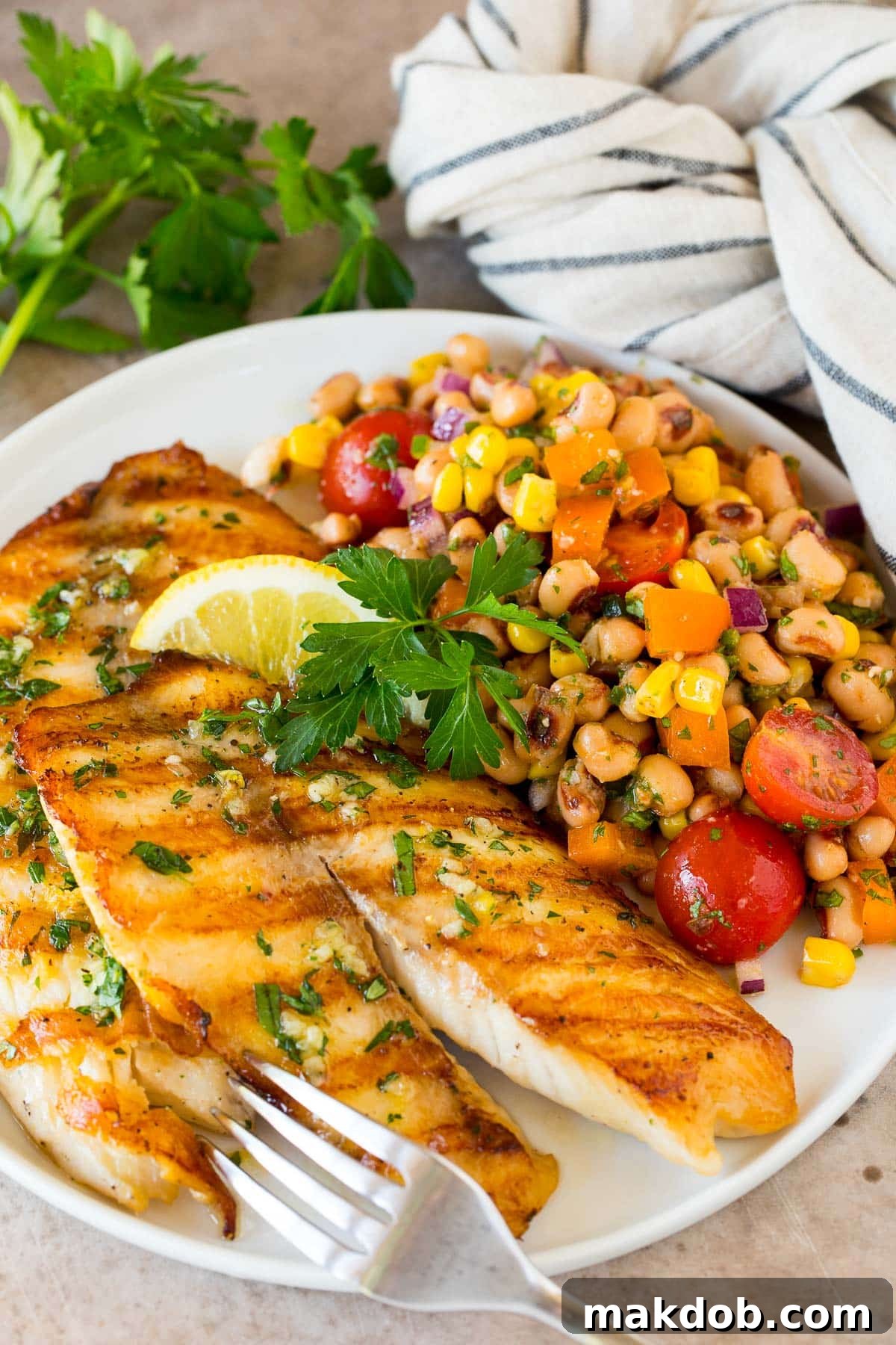 Zesty Black Eyed Pea Salad 6 A beautifully plated serving of black eyed pea salad next to a piece of perfectly grilled white fish, suggesting a light and healthy meal.