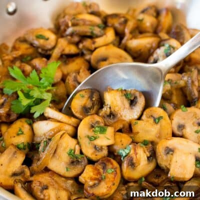 A spoon serving up a portion of sautéed mushrooms and onions.