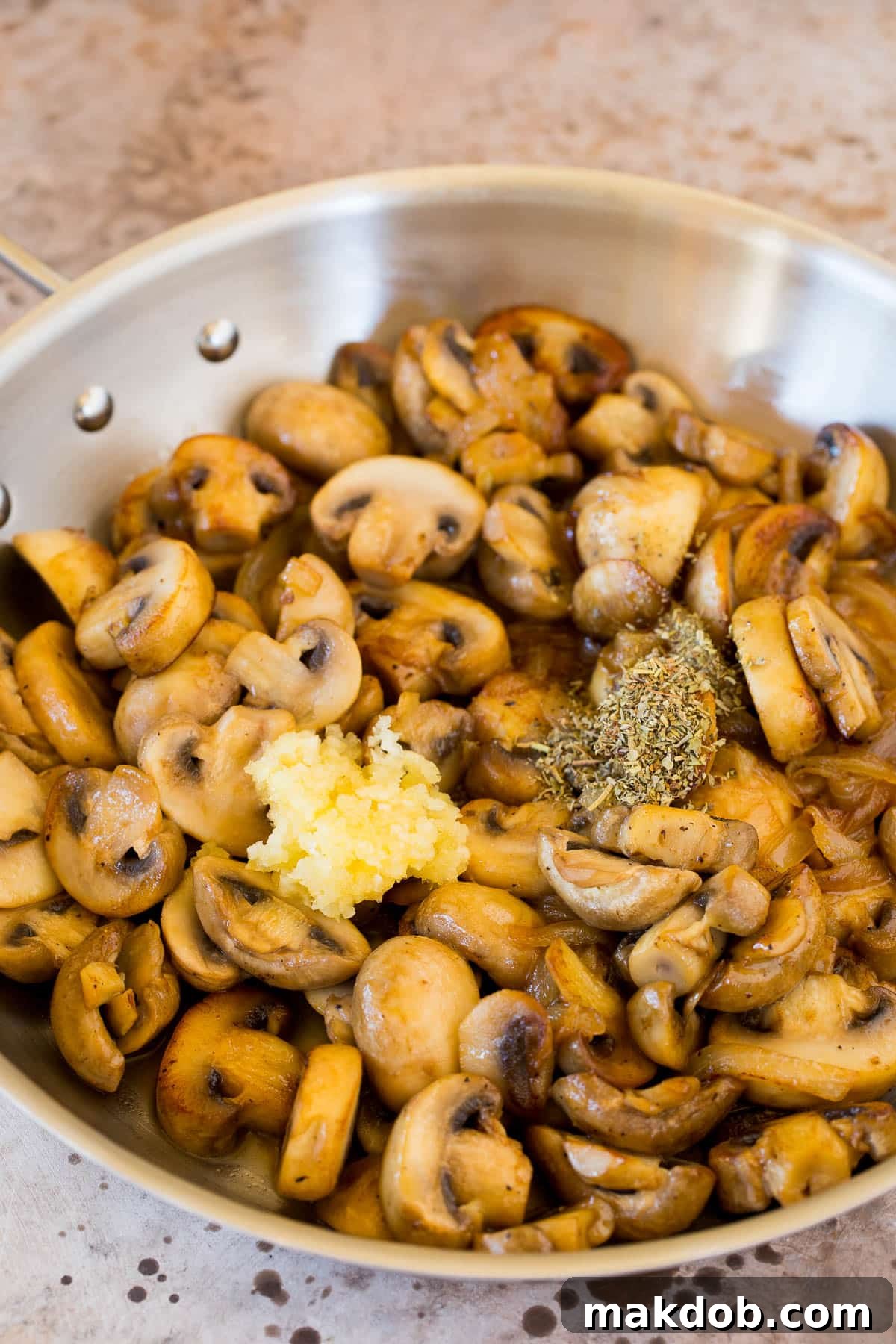Golden Sauteed Mushrooms and Onions 5 Close-up of golden-brown sautéed mushrooms, perfectly seasoned with garlic, salt, and pepper, glistening in a pan.