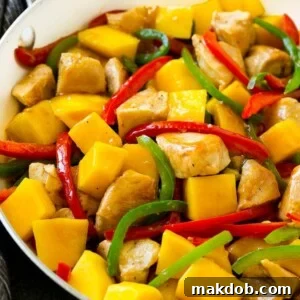 Bright and flavorful mango chicken in a skillet, garnished with vibrant red and green sliced bell peppers.