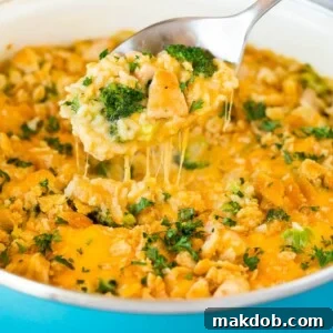 20 Easy One-Pot Chicken Dinners 7 A spoon serving up a portion of creamy and cheesy chicken broccoli casserole, topped with a crunchy crust.