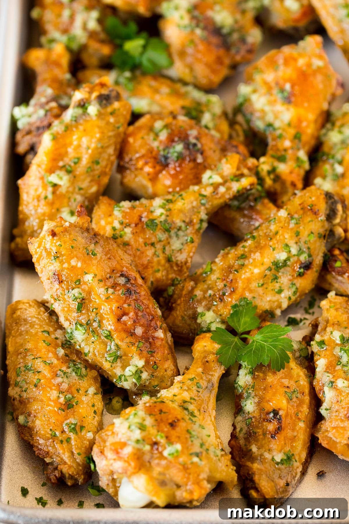 A pan of crispy garlic parmesan wings garnished with fresh parsley, ready to be served.