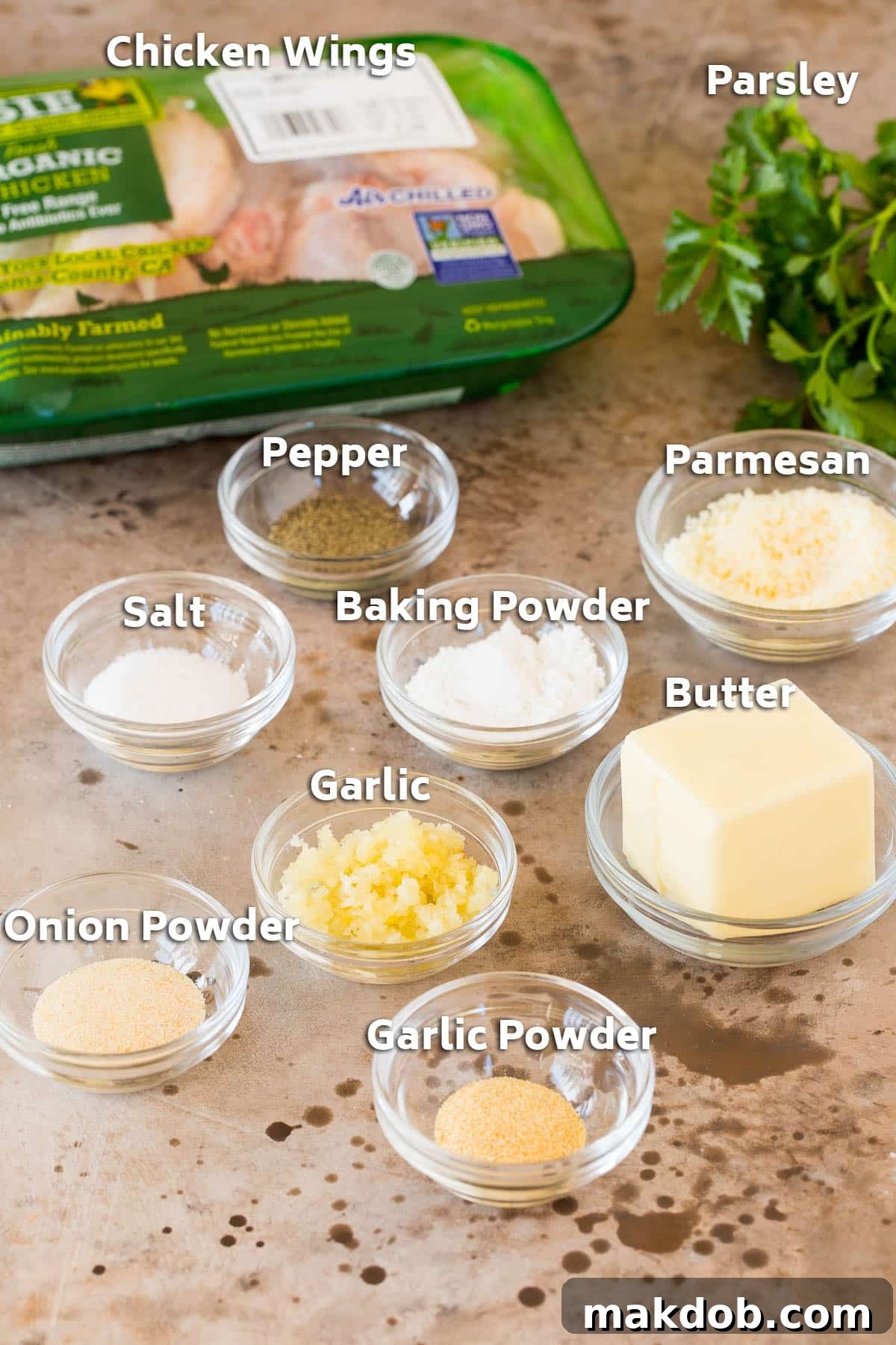 Ingredients for garlic parmesan wings, including fresh chicken, butter, a variety of seasonings, and grated cheese.