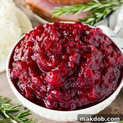 Instant Pot Cranberry Delight 7 A bowl of Instant Pot cranberry sauce garnished with rosemary.