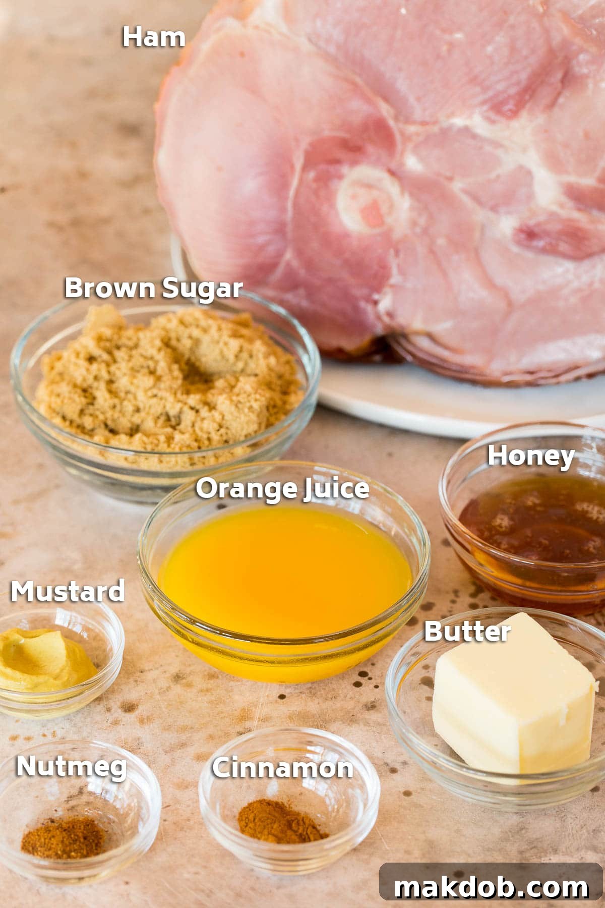 Sweet Glazed Easter Ham 3 A ham along with bowls of butter, brown sugar, honey, orange juice, Dijon mustard, cinnamon, and nutmeg, which are the ingredients for the glaze.