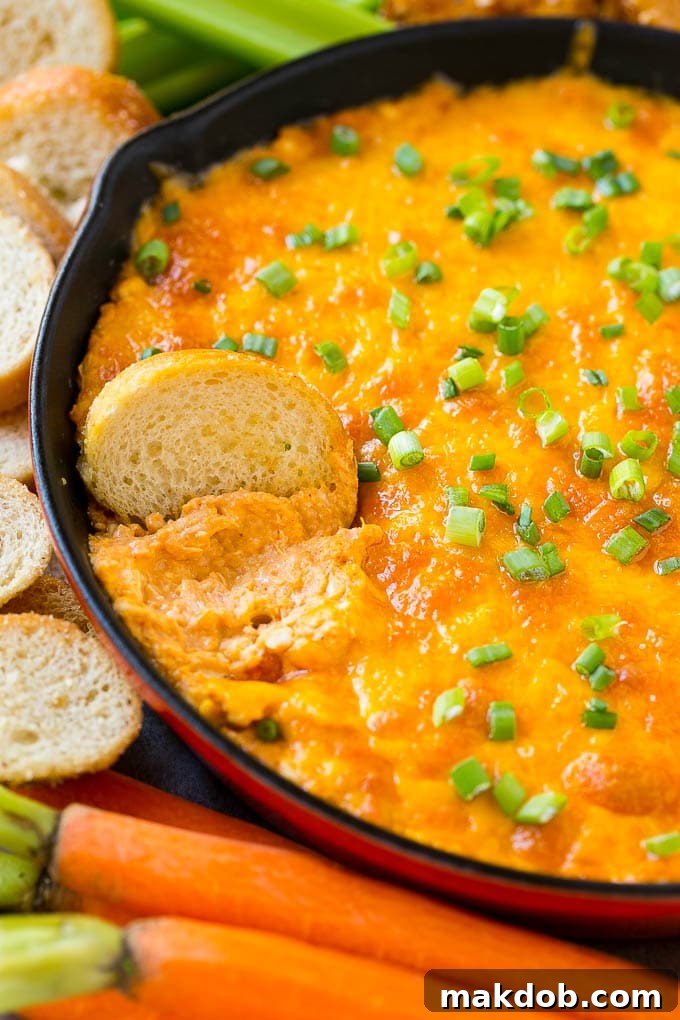 Buffalo Ranch Chicken Dip | Buffalo Chicken Dip | Baked Buffalo Dip | Cheesy Buffalo Dip #buffalowings #buffalochicken #dip #lowcarb #appetizer #dinneratthezoo Buffalo ranch chicken dip with a baguette slice in it.