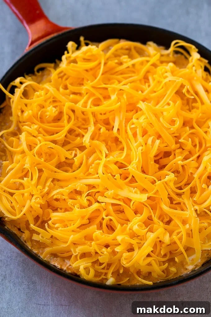 Buffalo Ranch Chicken Dip | Buffalo Chicken Dip | Baked Buffalo Dip | Cheesy Buffalo Dip #buffalowings #buffalochicken #dip #lowcarb #appetizer #dinneratthezoo Buffalo chicken dip topped with shredded cheddar cheese, ready to go into the oven.