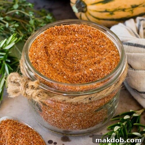 A jar of smoked turkey rub surrounded by herbs and winter squash.